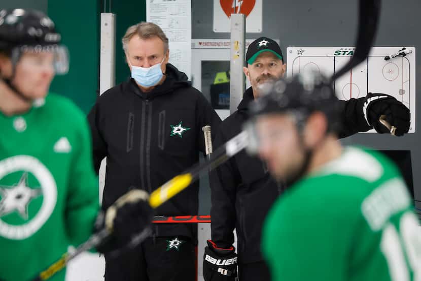 Stars head coach Rick Bowness (with mask) watches his team work out during training camp at...