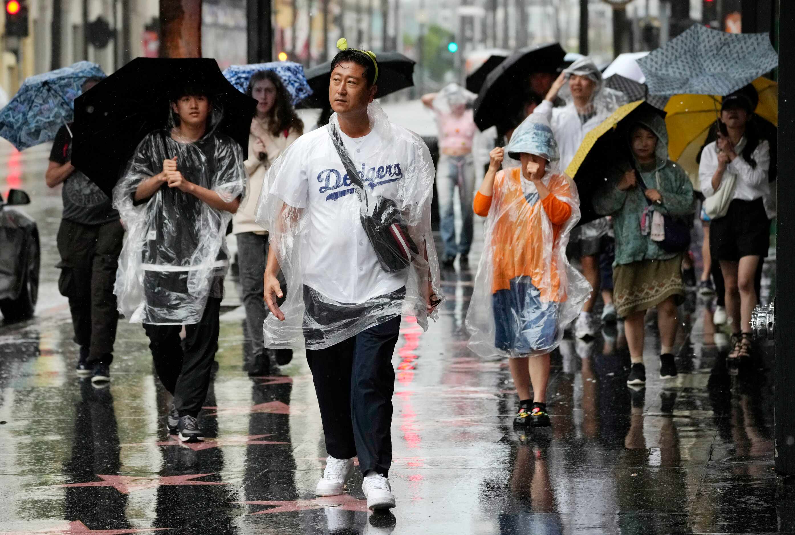 People walk through strong winds and rain on Hollywood Boulevard during Tropical Storm...