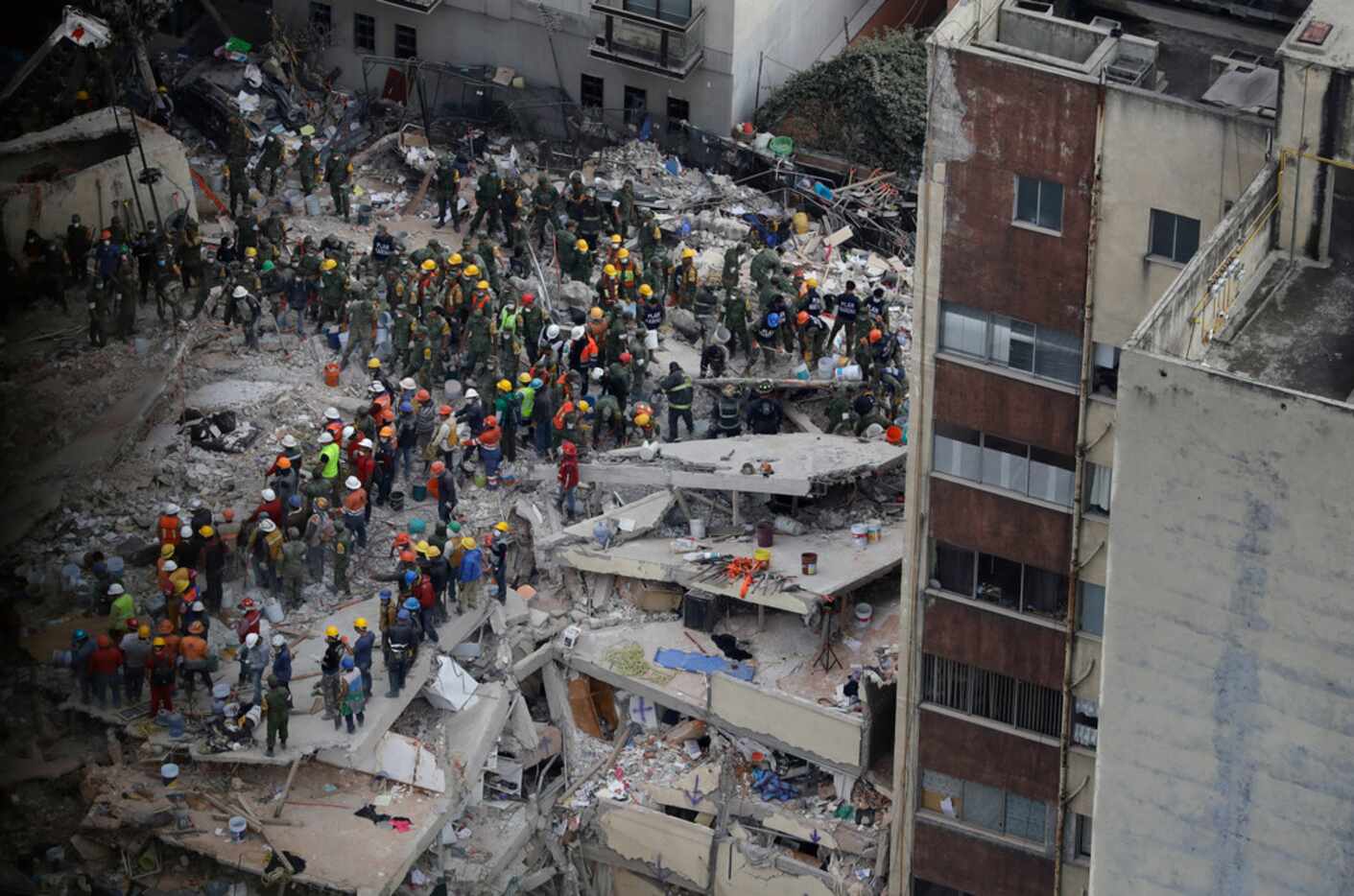 Rescue workers search for people trapped inside a collapsed building in the Del Valle area...