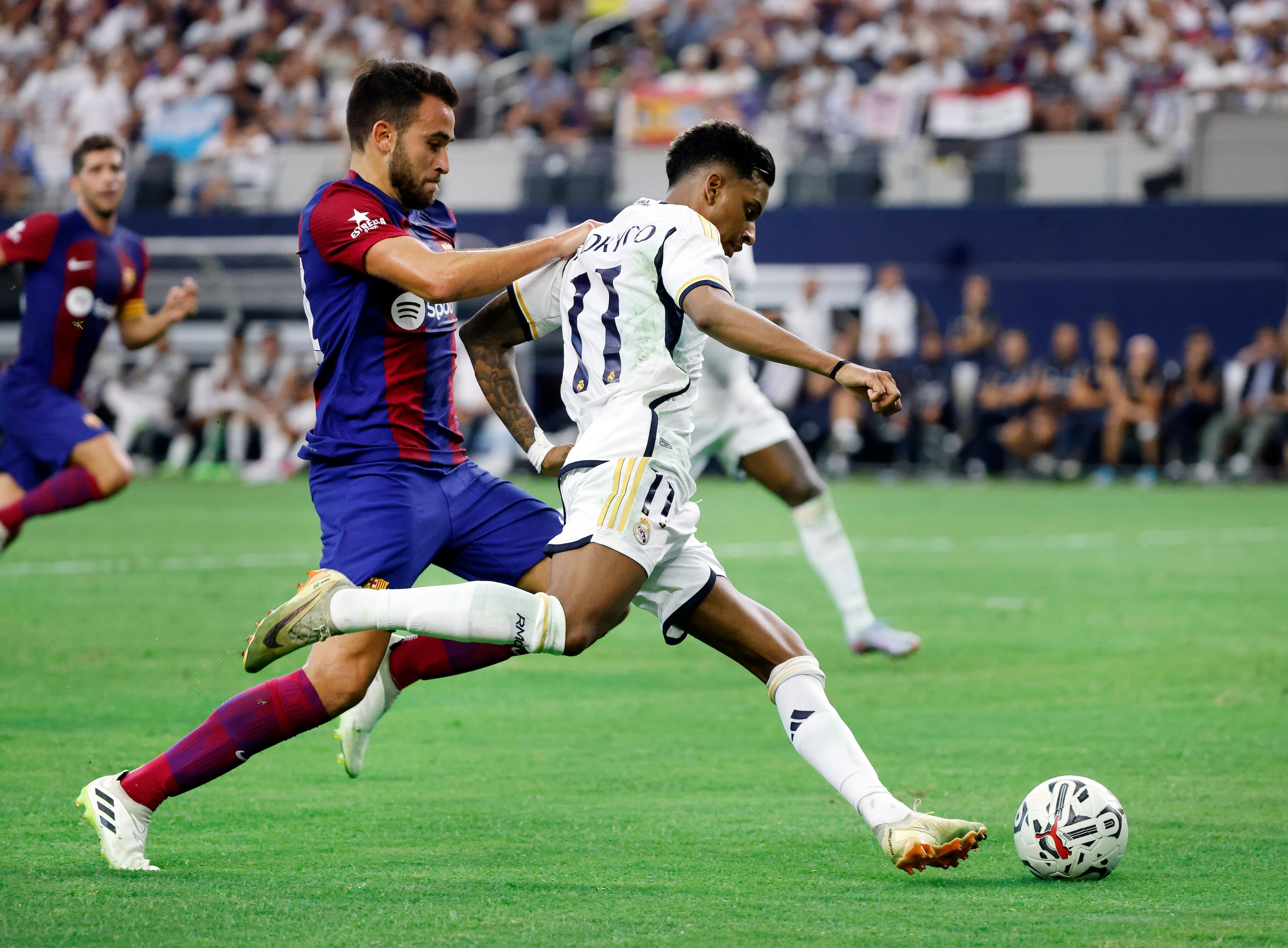 Real Madrid forward Marco Asensio (11) looks to score despite being held by Barcelona...