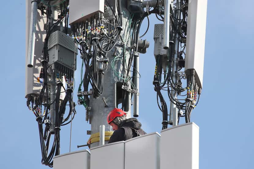A worker rebuilds a cellular tower with 5G equipment for the Verizon network on November 26,...