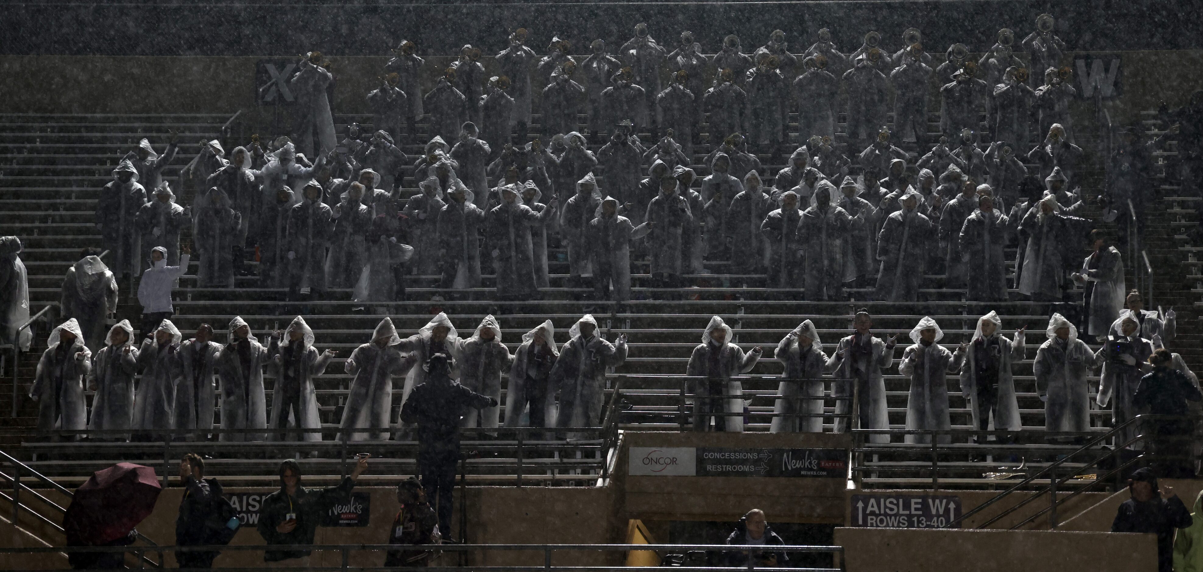 Members of the Lewisville band play the school song as light rain falls prior to the opening...