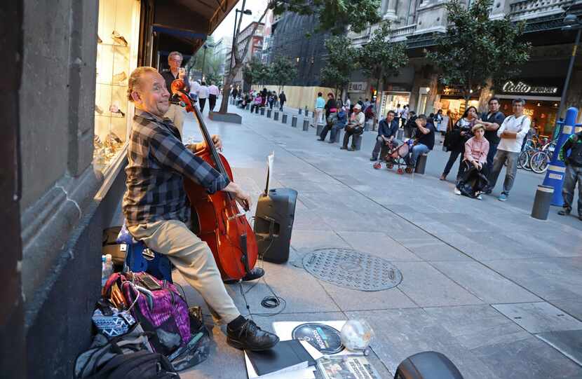 A musician plays for tips along September 16 Avenue, in front of a shoe shop near the Zocalo...