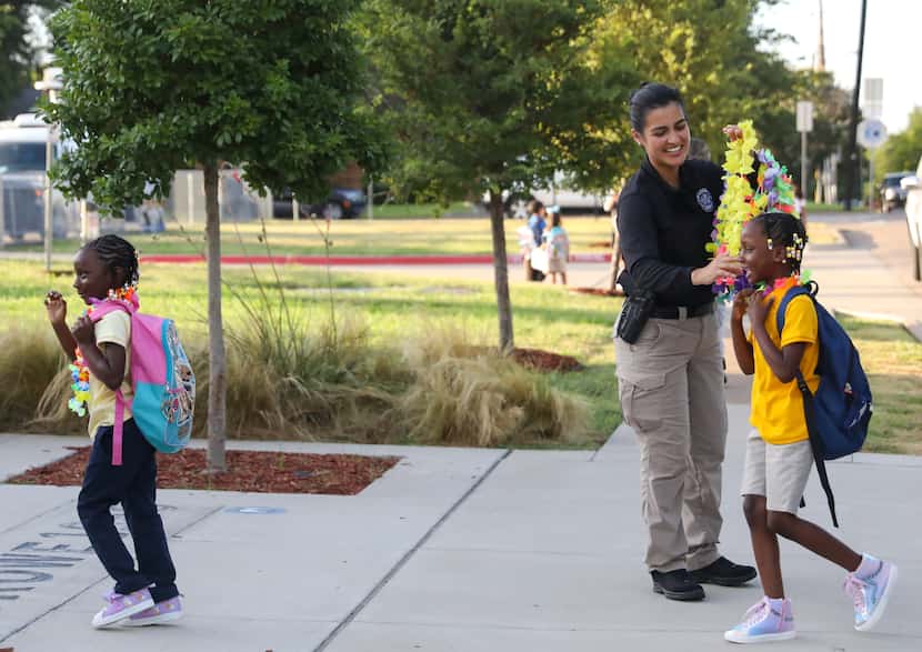 Students are greeted with leis from staff and local police officers, including Dallas Police...