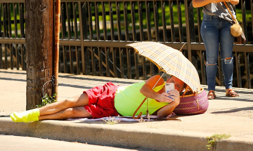 Richard Allen of North Dallas lies down on the sidewalk to record crews attempting to remove...