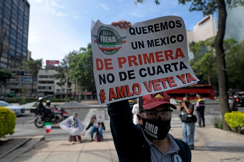 A man holds a sign reading "We want a first class Mexico, AMLO go away now," referring to...