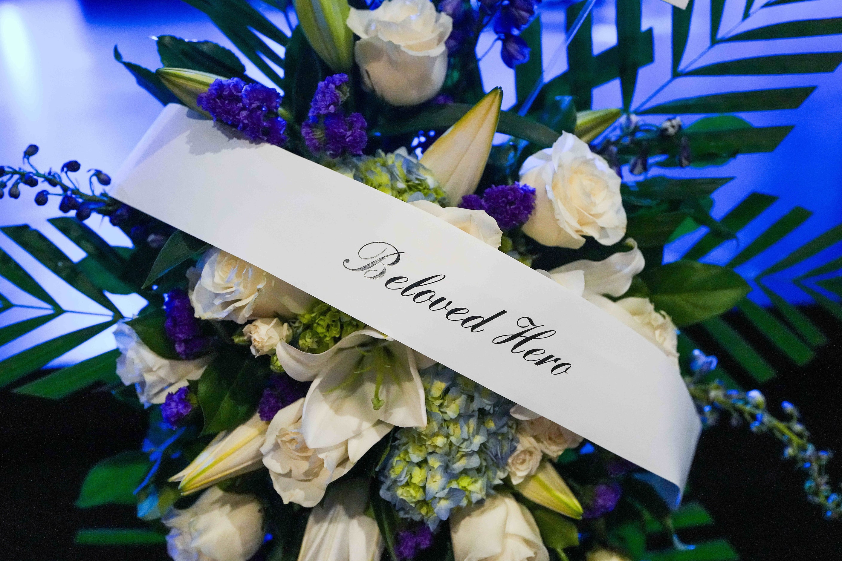 The banner on a floral arrangement reads “Beloved Hero” before funeral services for Dallas...