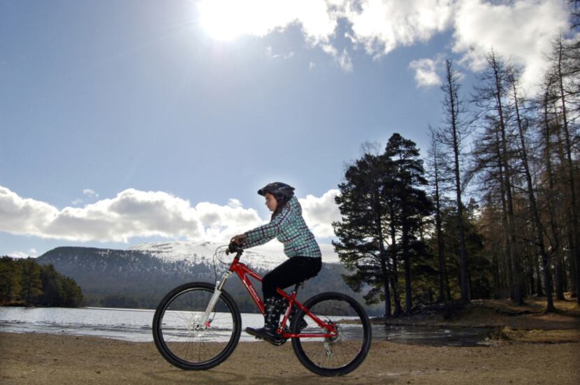 Cycling past Loch an Eilein at Rothiemurchus Estate in Cairngorms National Park near...