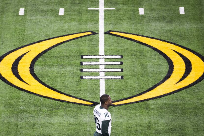 Michigan State wide receiver Aaron Burbridge passes the CFP logo as he walks across the...