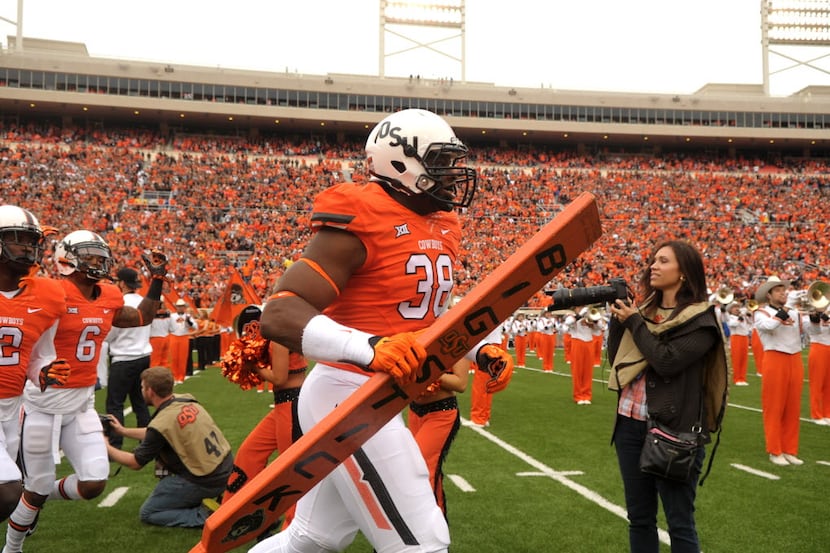 Oklahoma State defensive end Emmanuel Ogbah (38) carries the team's "Big Stick" onto the...