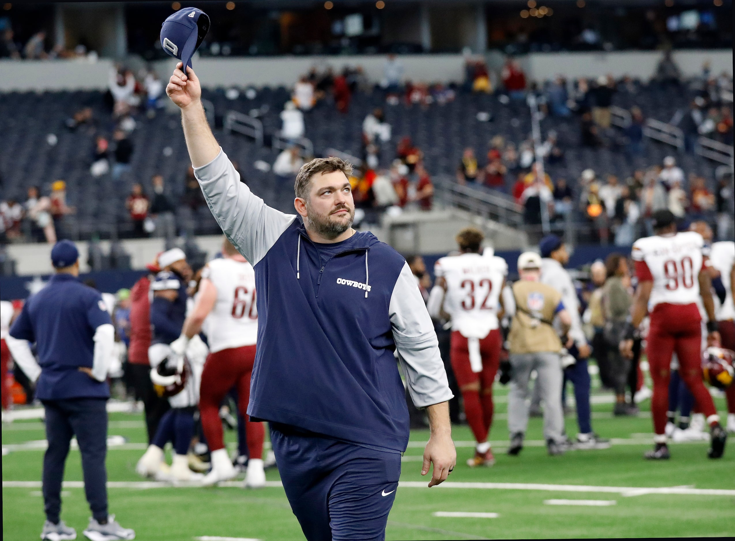 Injured Dallas Cowboys guard Zack Martin tips his hat to fans as he exits the field...