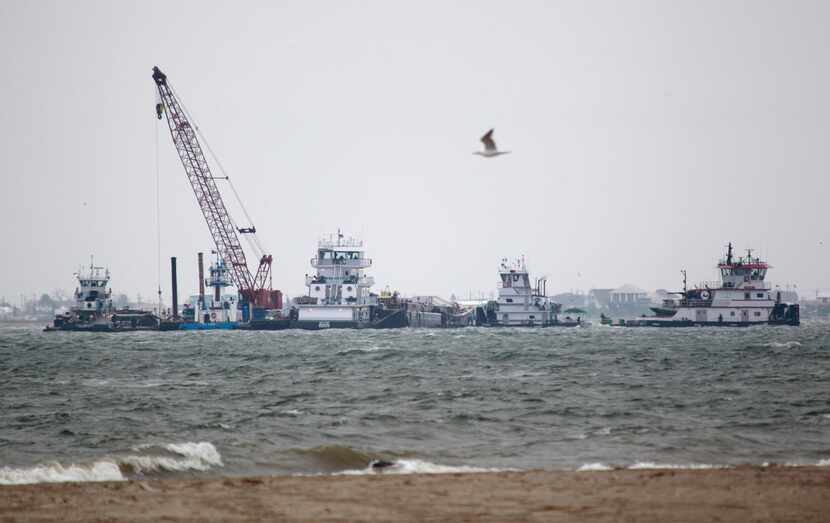 Emergency crews worked along a barge that spilled oil after it was struck by a ship near the...