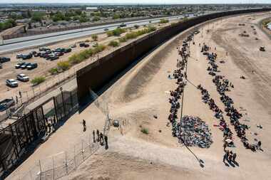 Migrants form lines outside the border fence waiting for transportation to a U.S. Border...