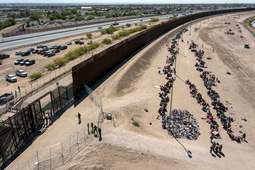Migrants form lines outside the border fence waiting for transportation to a U.S. Border...