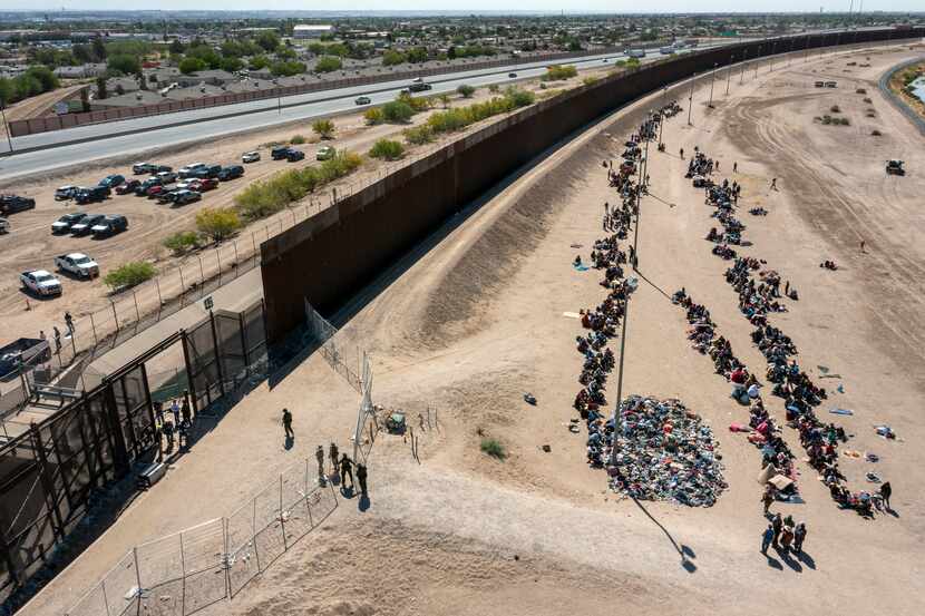 FILE - Migrants form lines outside the border fence waiting for transportation to a U.S....