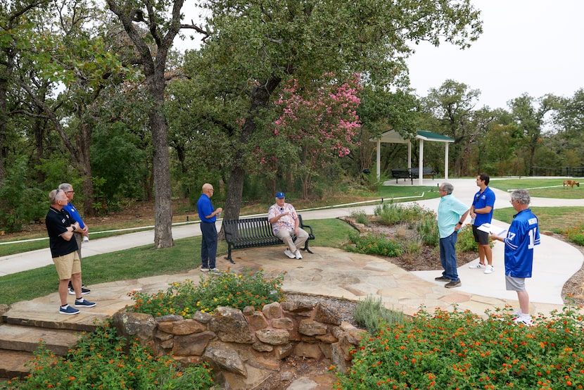 Dale Hansen (center) reminisces while sitting on a bench at a walking trail on the property...