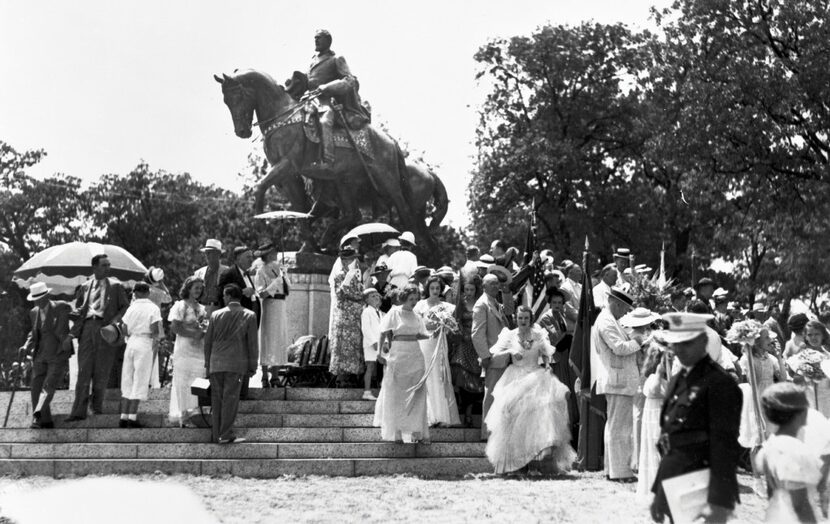 Dressed for a celebratory occasion, a crowd mills about the newly unveiled statue of Robert...