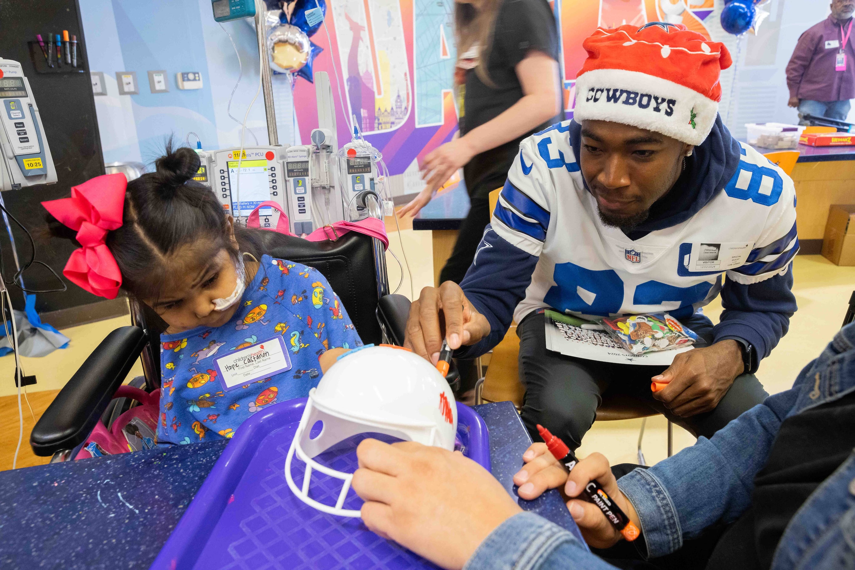 Dallas Cowboys wide receiver Jalen Brooks (83) and Hope Castanon, 7, draw on a helmet at...