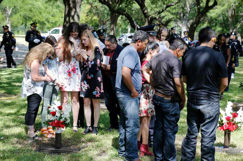 Families of fallen officers prayed after placing flowers at gravesites during the Dallas...