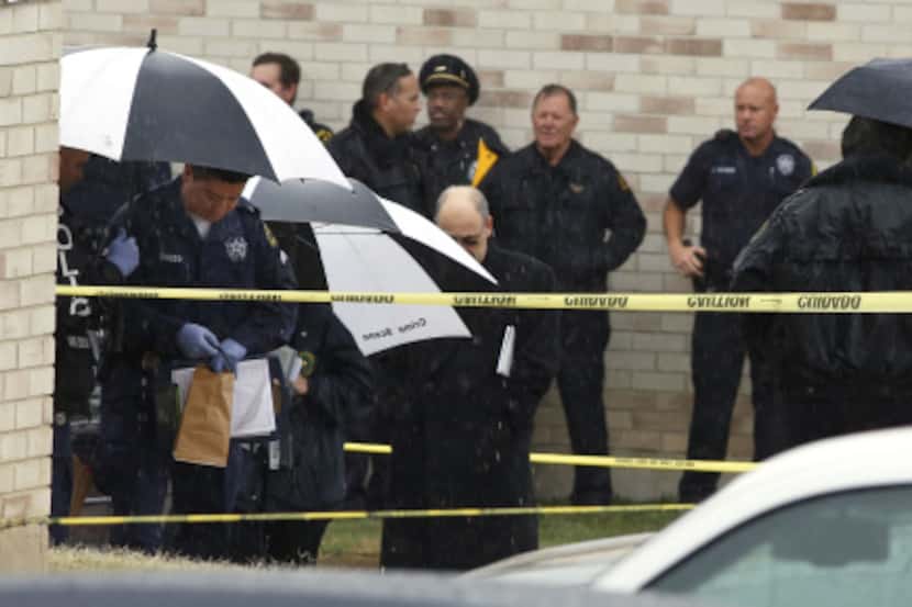 Dallas police officers collect evidence after an officer shot and killed a man at a west Oak...
