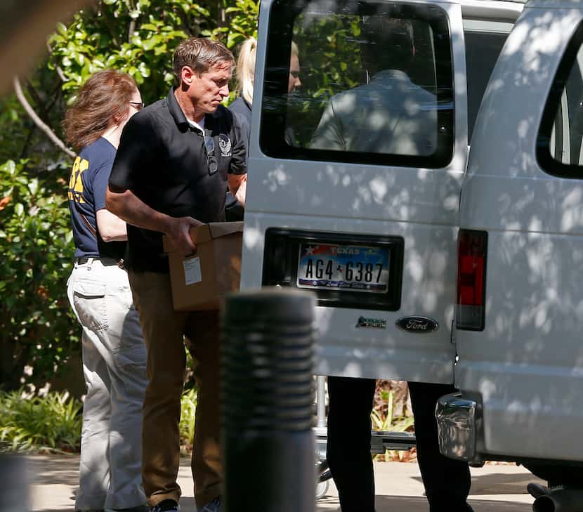A federal agent loads boxes into a van at Medoc Health Services in Dallas on Wednesday.