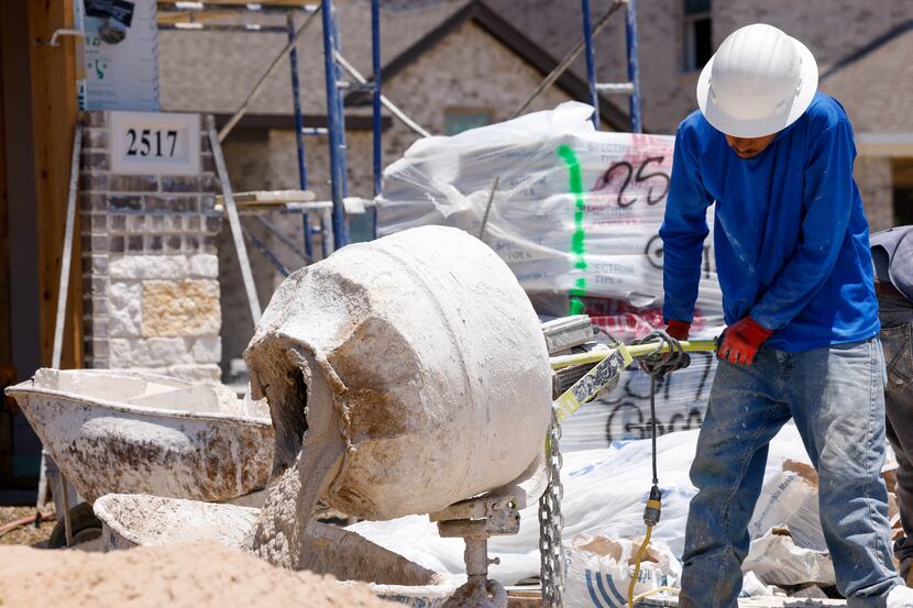 A construction worker pours a mixture for laying bricks on a new home on July 13, 2023.