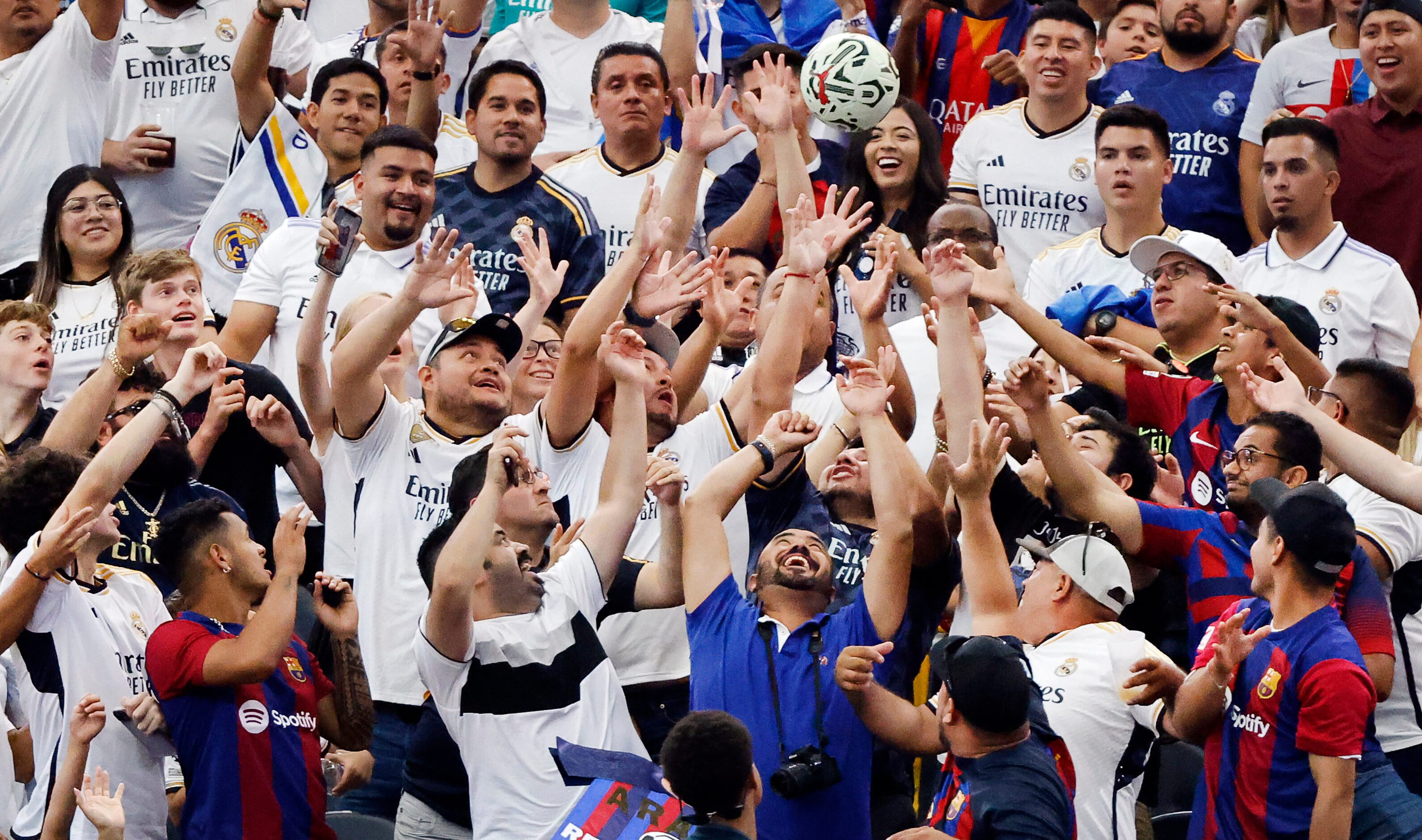 Real Madrid fans reach for a game ball that was kicked into the lower seating area during...