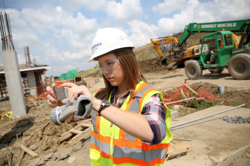 Amanda Calvert, an intern with Skanska construction, takes a photo of the construction...