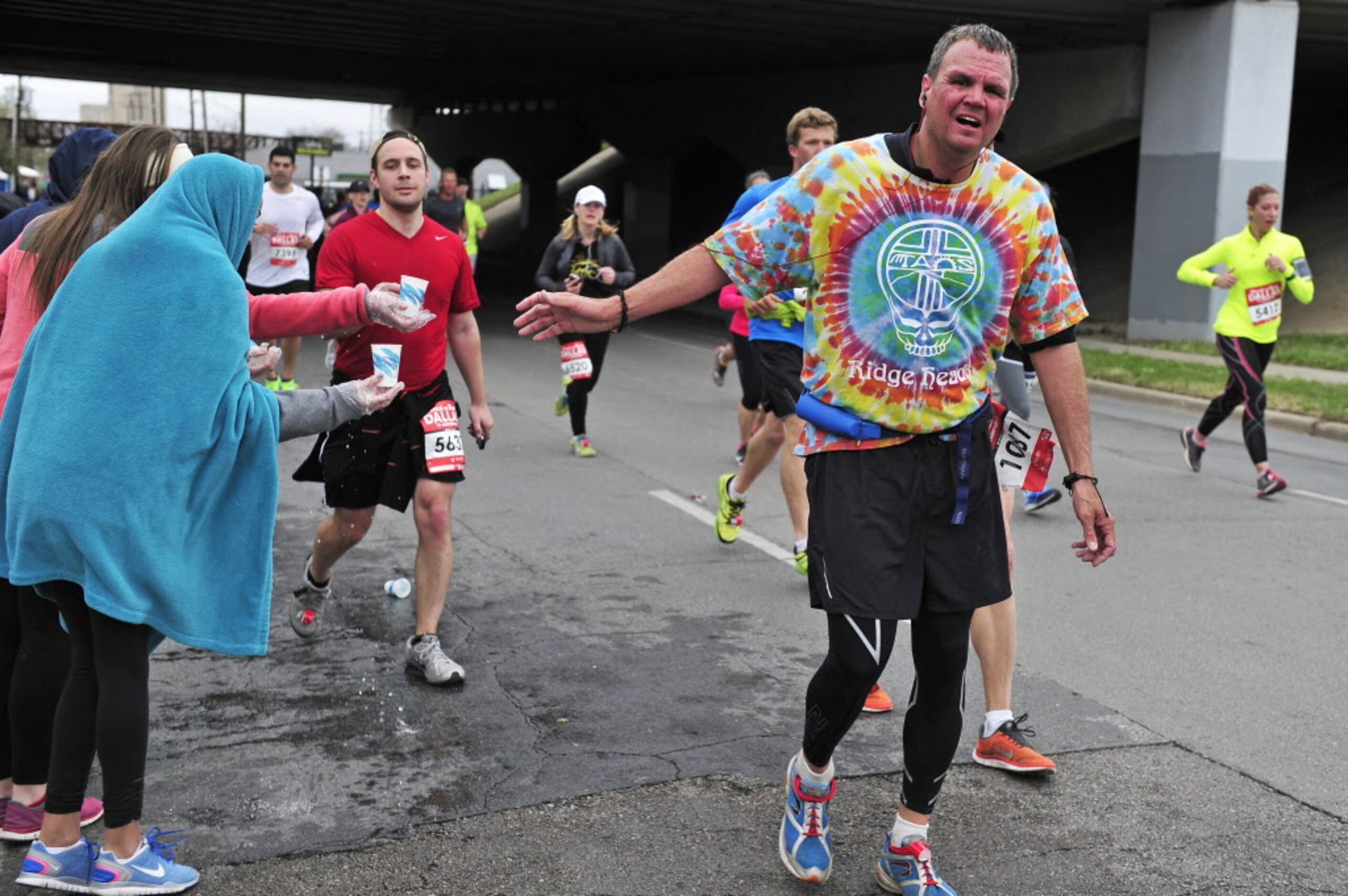 Runners take water from volunteers at a water station during the Dallas Rock N' Roll...