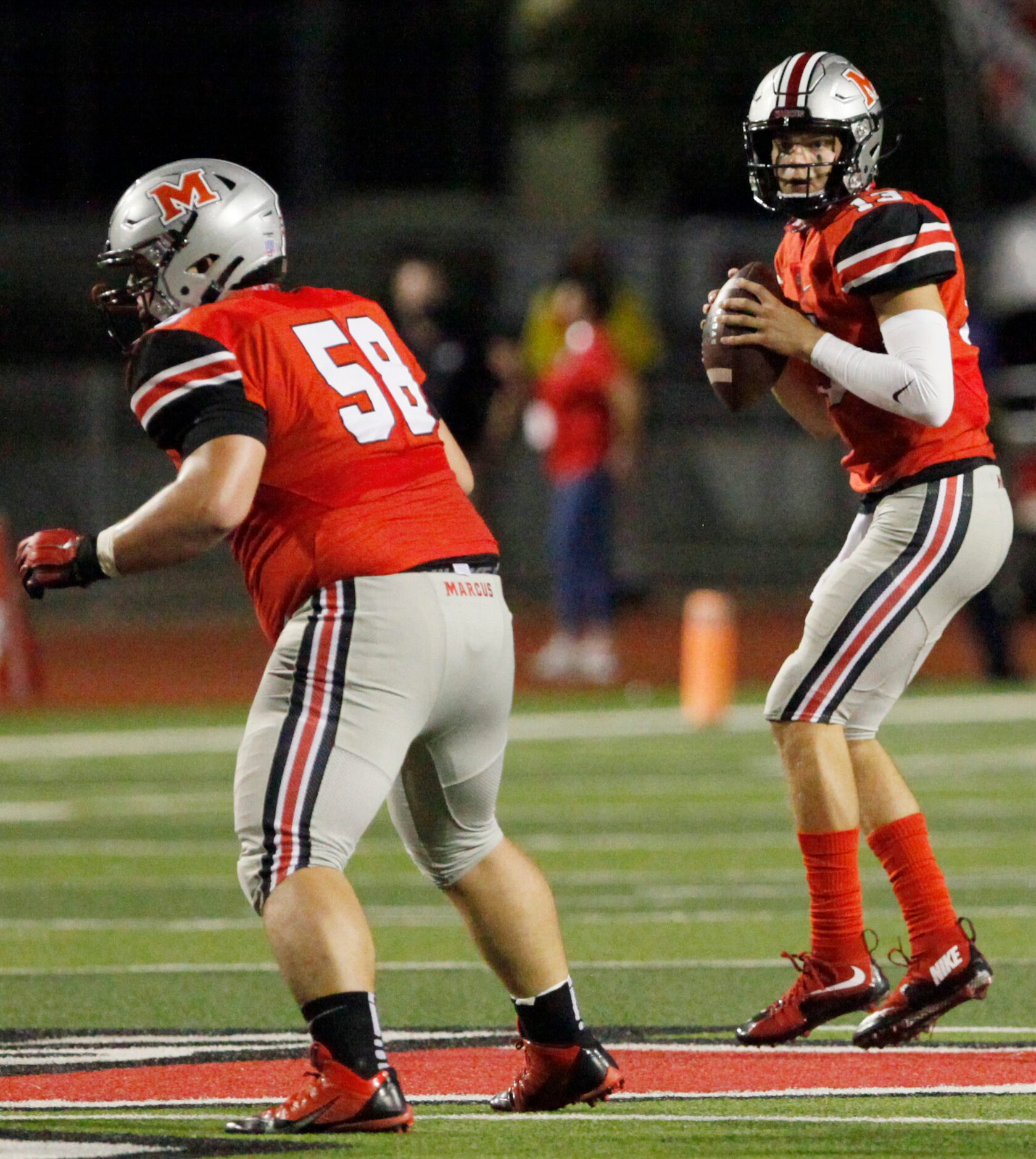 Flower Mound Marcus senior quarterback Garrett Nussmeier (13) looks down field for a wide...