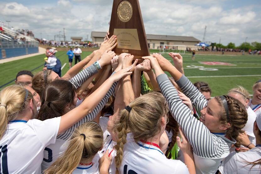 Highland Park players hoist up their state championship trophy after their win over Aledo...