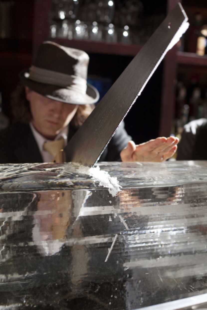 Mixologist and co-owner Eddie "Lucky" Campbell saws ice into small blocks to chip artisanal...