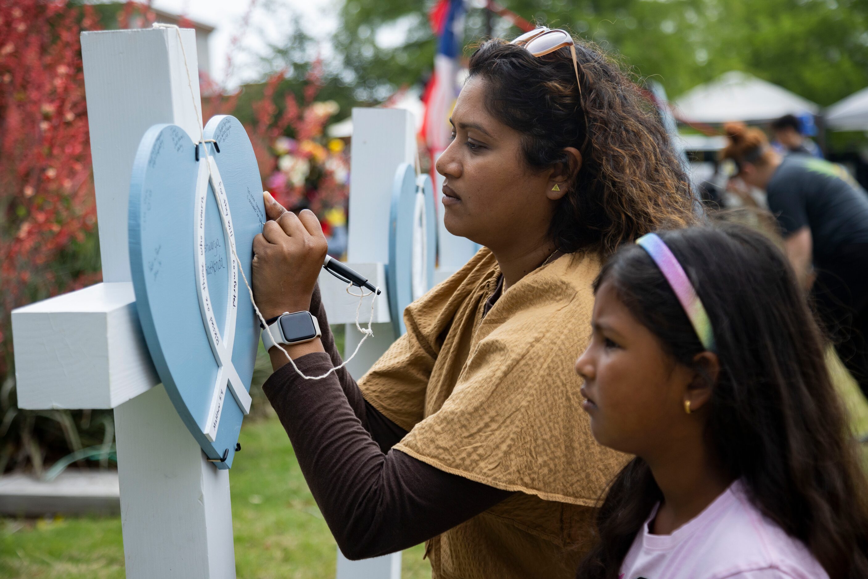 Shwetha Sridharan and daughter Medha Shamasunder, 7, write on a cross for Aishwarya...