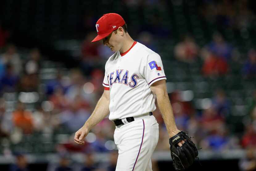 Texas Rangers' Sam Dyson walks to the dugout after the top of the 10th inning of a baseball...