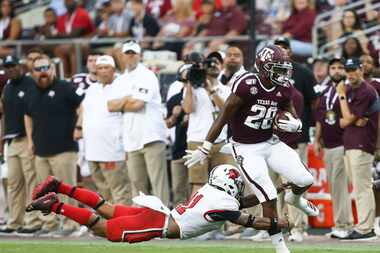 Isaiah Spiller #28 of the Texas A&M Aggies is tackled from behind by Michael Lawson #41 of...