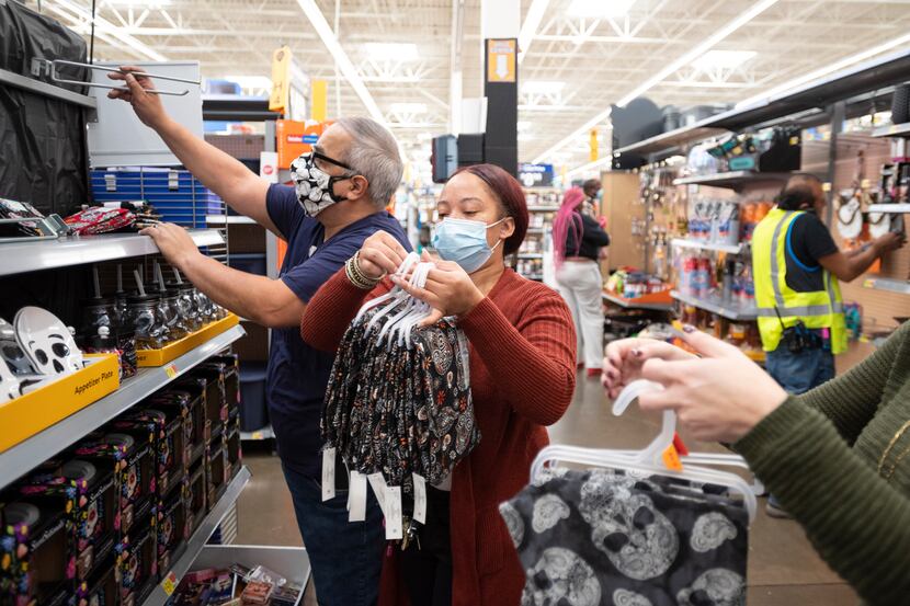 Walmart employees Roberto Bustos, left, and Ron Adams, center, re stock a shelf with their...