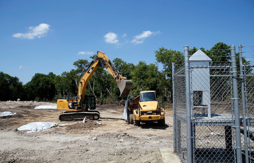 Crews excavate in a vacant lot where battery chips were found across the street from the old...