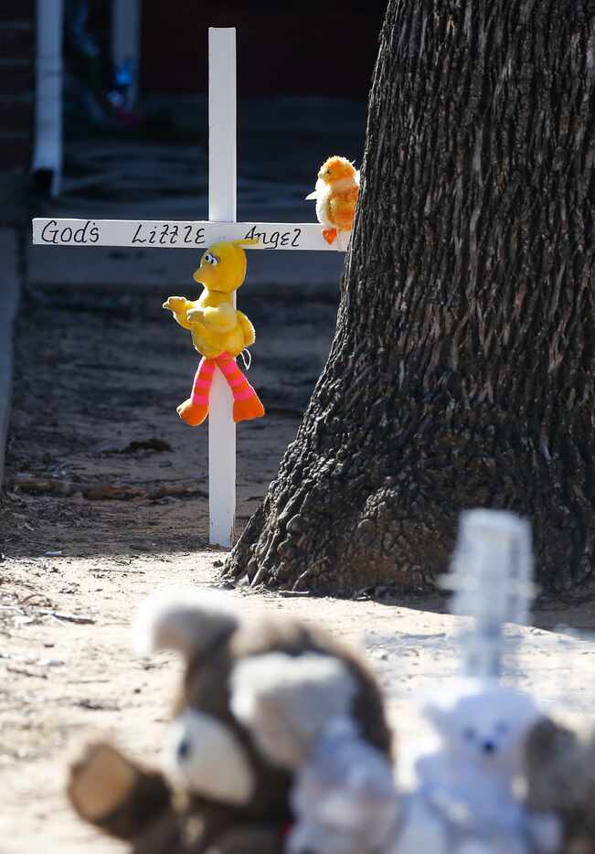 A memorial is seen Tuesday, Jan. 7, 2020, along the sidewalk of a home where a shooting left...