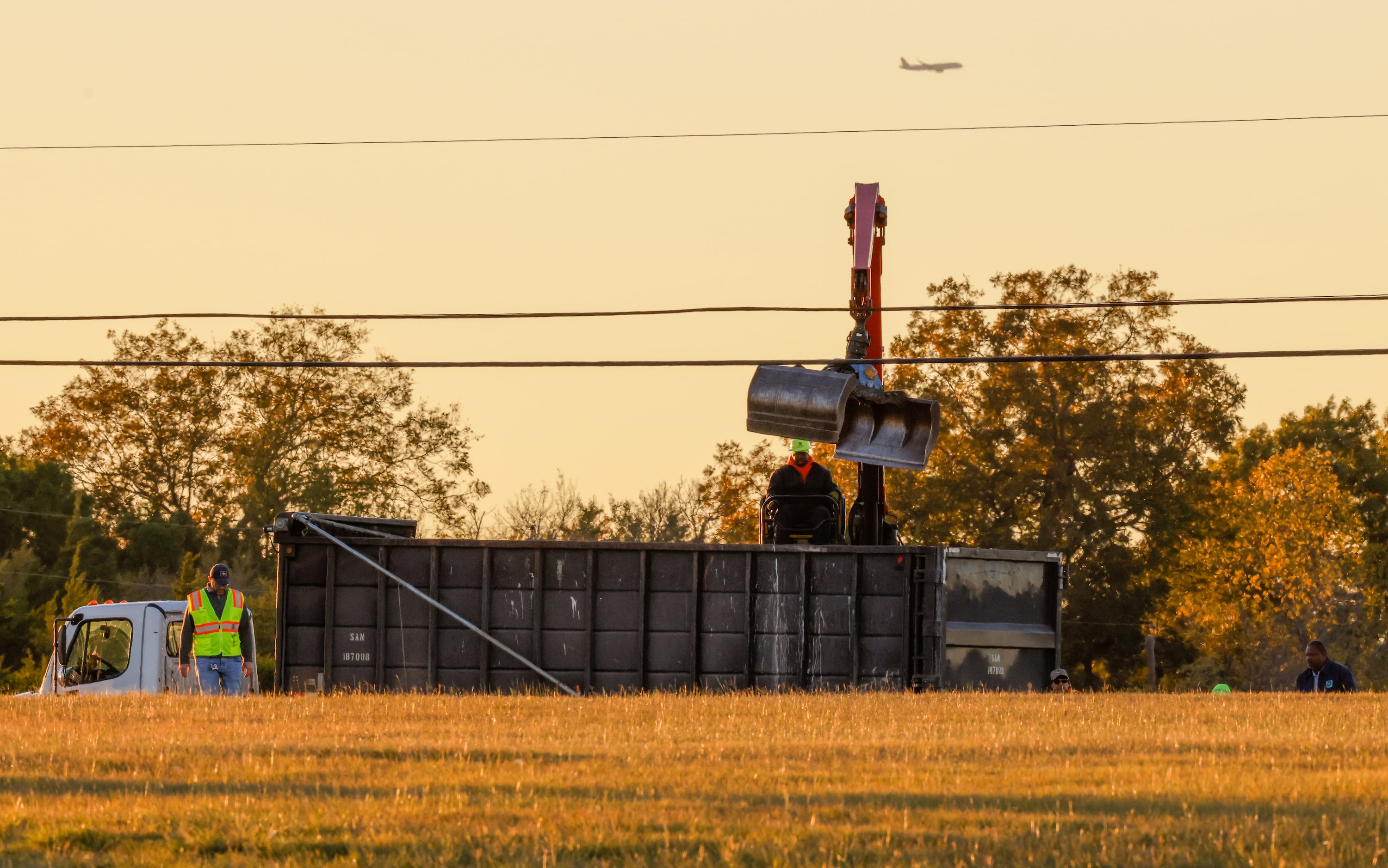 Workers pick up debris from a mid-air collision between two planes at the Dallas Executive...