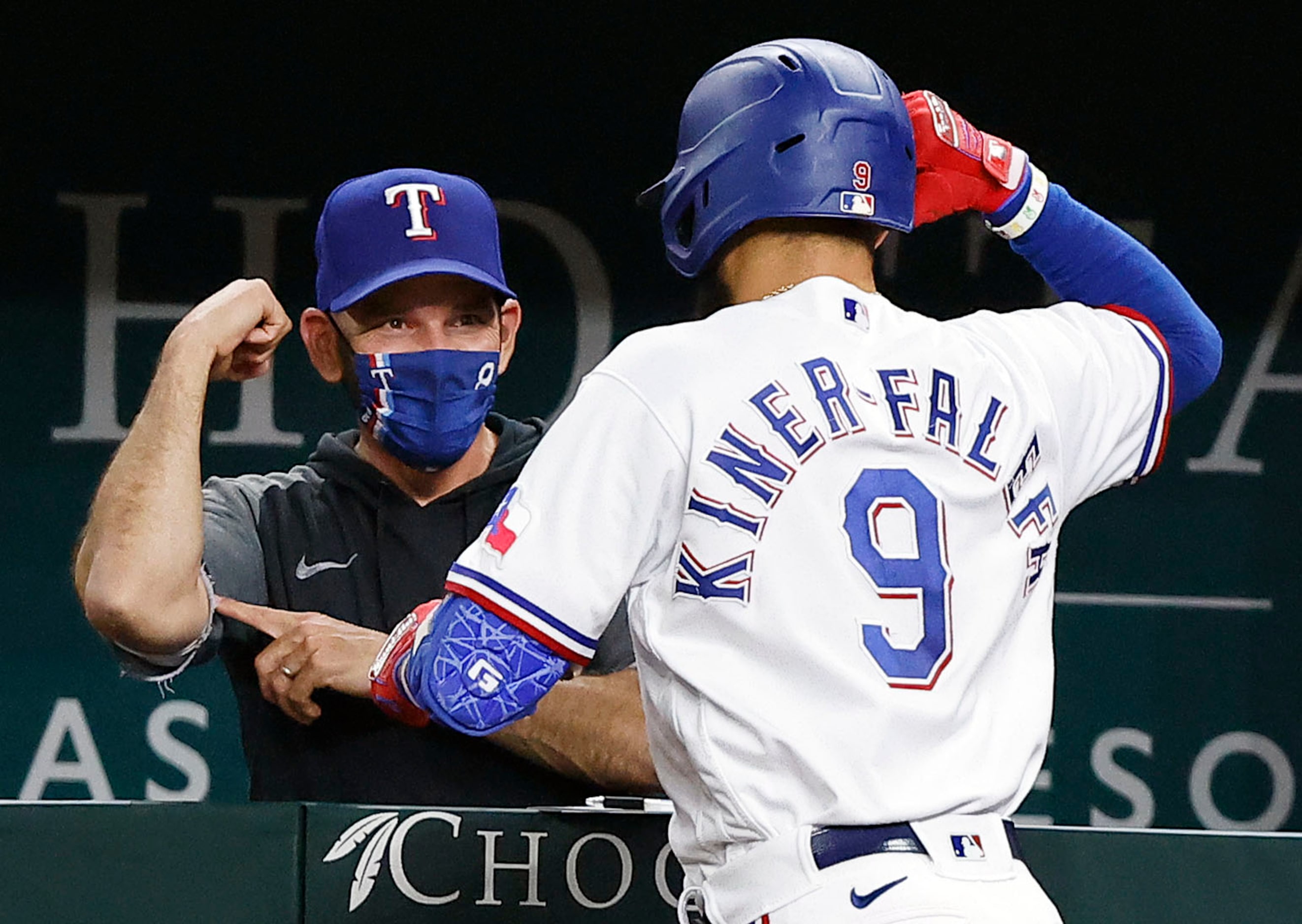 Texas Rangers manager flexes his muscle as he congratulates Isiah Kiner-Falefa (9) on his...