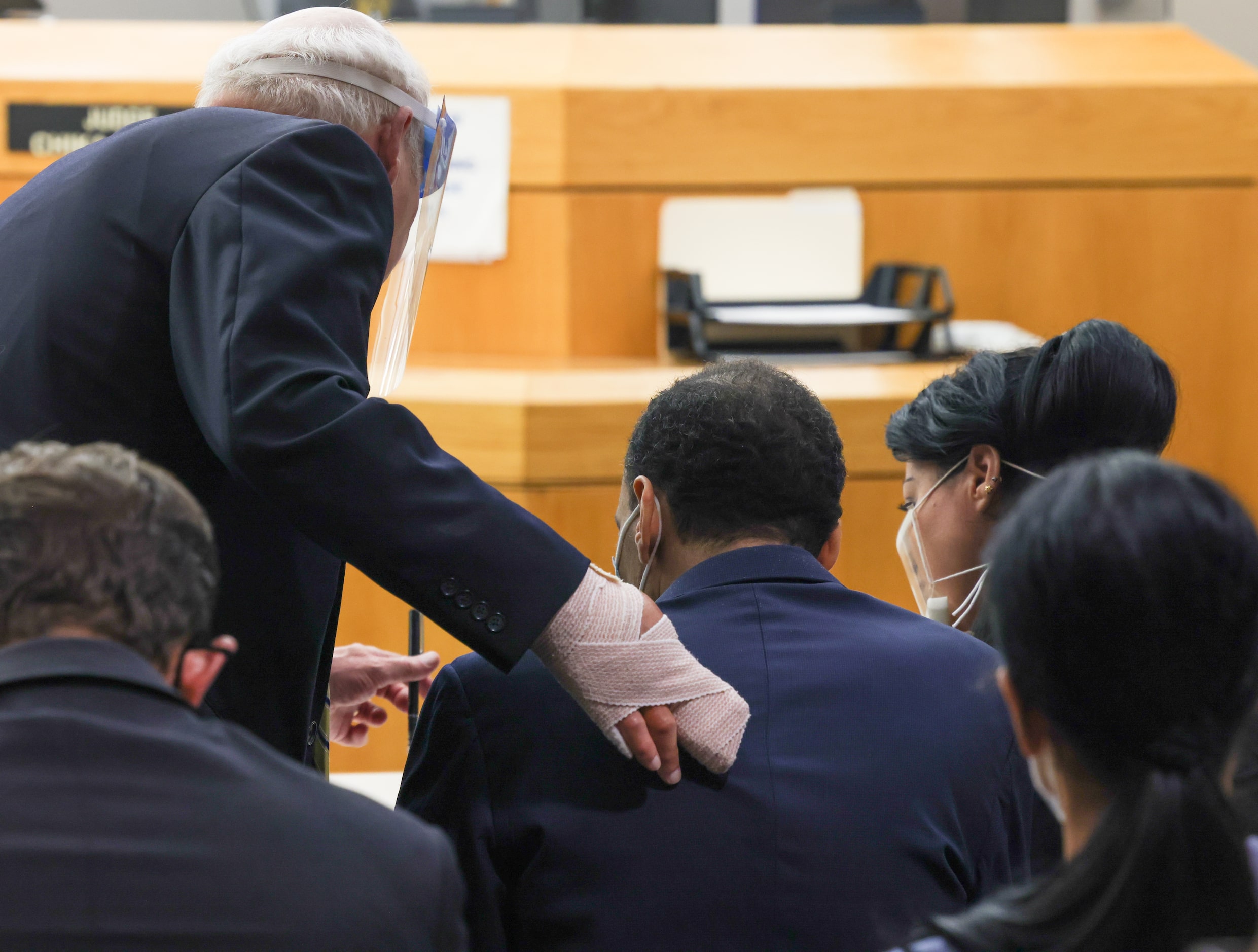 Defense lawyer Brad Lollar (left) holds out a pen to Yaser Said (center) to sign a document...