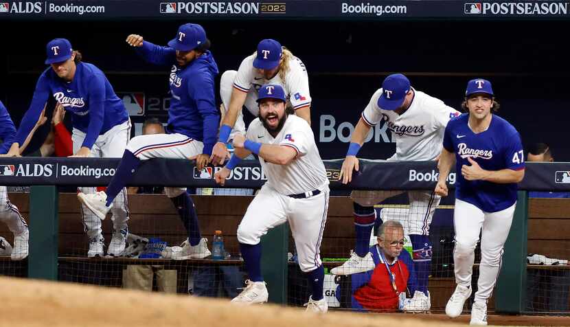 Texas Rangers players, including catcher Austin Hedges (center) pour out of the dugout...