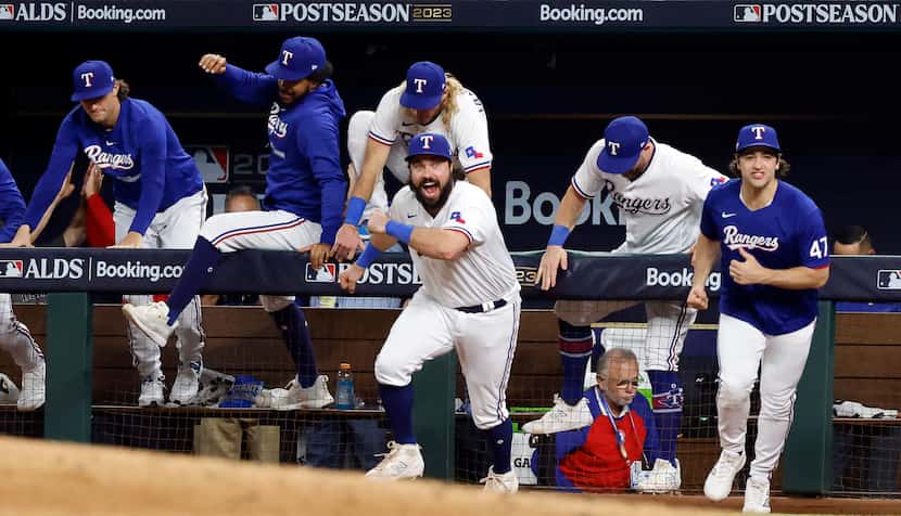 Texas Rangers players, including catcher Austin Hedges (center) pour out of the dugout...