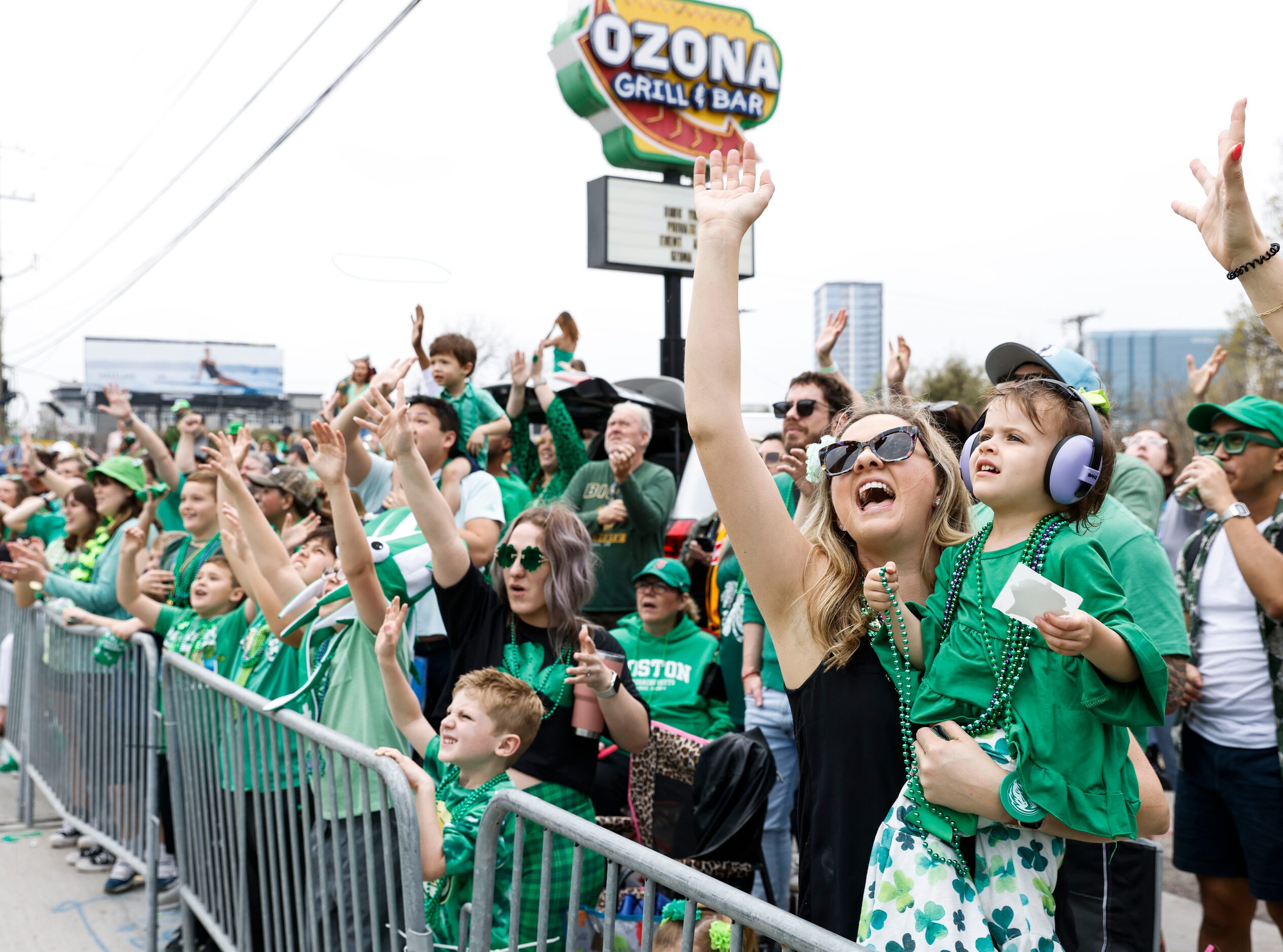 Attending crowd tries to catch green bead necklaces tossed by marchers during a Saint...