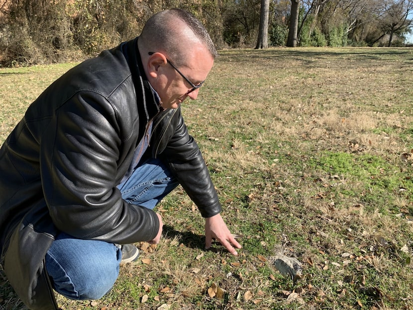 Dan Babb inspects one of the surviving markers at the old Dallas City Cemetery, which has...