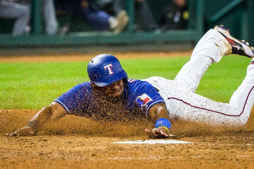 Texas Rangers shortstop Elvis Andrus slides home to score on a passed ball during the sixth...