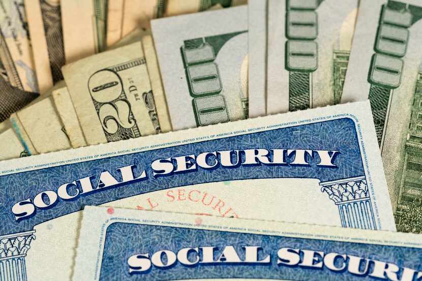 Tarjetas del Seguro Social encima de varios billetes de dolar. iStock.
