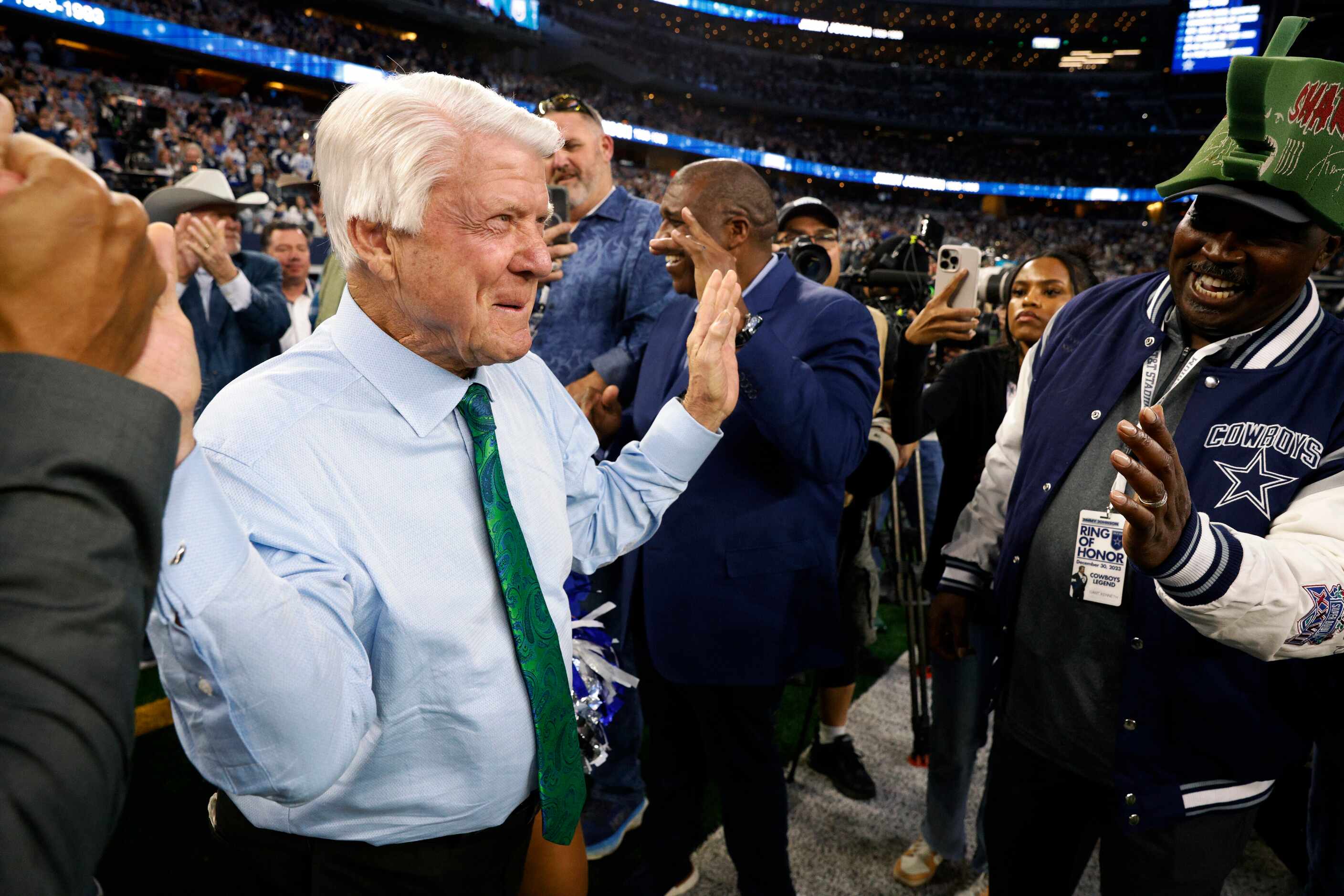 Former Dallas Cowboys head coach Jimmy Johnson high-fives former players and guests during a...