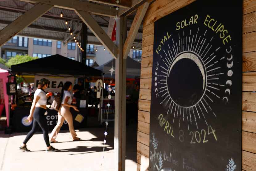 People walk by a solar eclipse sign on Sunday, April 7, 2024 at Dallas Farmers Market....