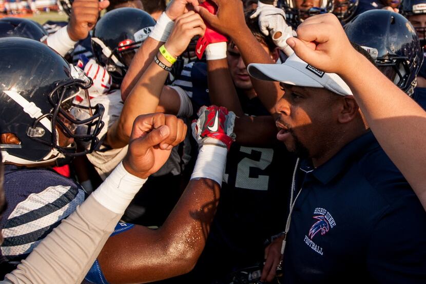 Bishop Dunne's head football coach Michael Johnson talks to his team before a scrimmage...